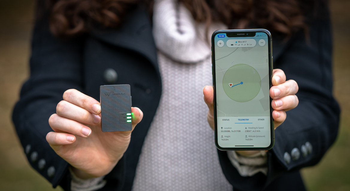 Person holding Dronetag Mini and Dronetag Mobile App on a mobile phone